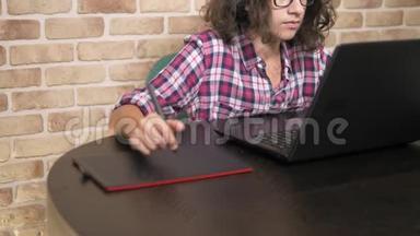 差不多了。 一个少年，头发卷曲，黑发，穿着格子衬衫，使用手写笔在一个图形平板上工作